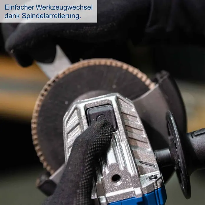 Scheppach IXES 20V Akku-Winkelschleifer BC-AG125-X - 20 V, Ohne Akku, Durchmesser Scheibe: 125 mm - Behandschuhte Hand drückt den Spindelarretierungsknopf eines silbernen Winkelschleifers mit Trennscheibe für einfachen Werkzeugwechsel.