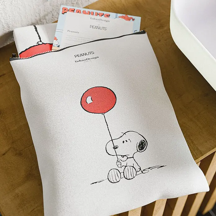 Tohaa Design Duschvorhang Snoopy Balloon - Peanuts -  - Helle Stofftasche mit Snoopy und rotem Ballon, offen auf Holzfläche mit Papieren.
