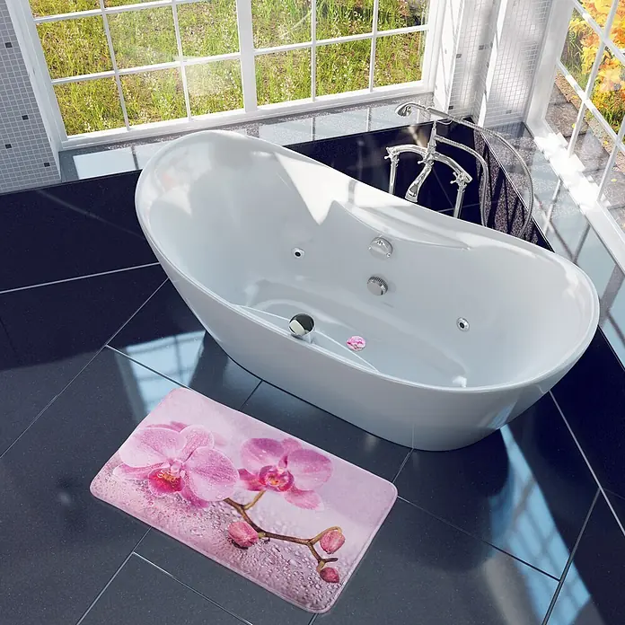SANILO Badteppich Blooming 50 x 80 cm - 50 x 80 cm, Polyester, Rosa - Rosa Badematte mit lebhaftem Orchideen- und Wassertropfenmuster auf dunklem Fliesenboden neben einer weißen Badewanne.