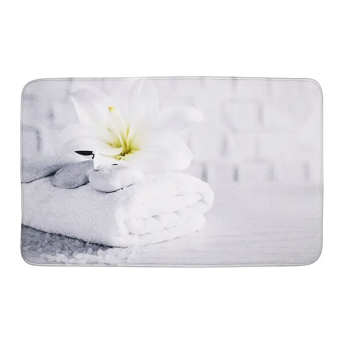 SANILO Badteppich Good Feeling 70 x 110 cm - 70 x 110 cm, Polyester, Weiß - Rechteckige Badematte mit aufgedrucktem Design aus weißer Lilie, Spa-Steinen und gefaltetem Handtuch für Wellness-Atmosphäre.