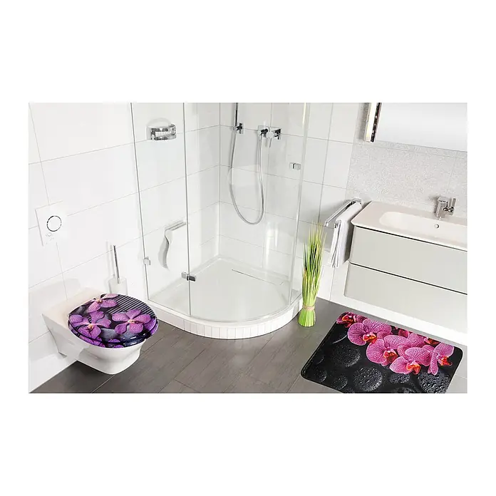 SANILO Badteppich Madeira 50 x 80 cm - 50 x 80 cm, Polyester, Lila - Toilettensitz und Badematte mit leuchtendem Orchideen- und schwarzem Steindesign, in modernem Badezimmer gezeigt.