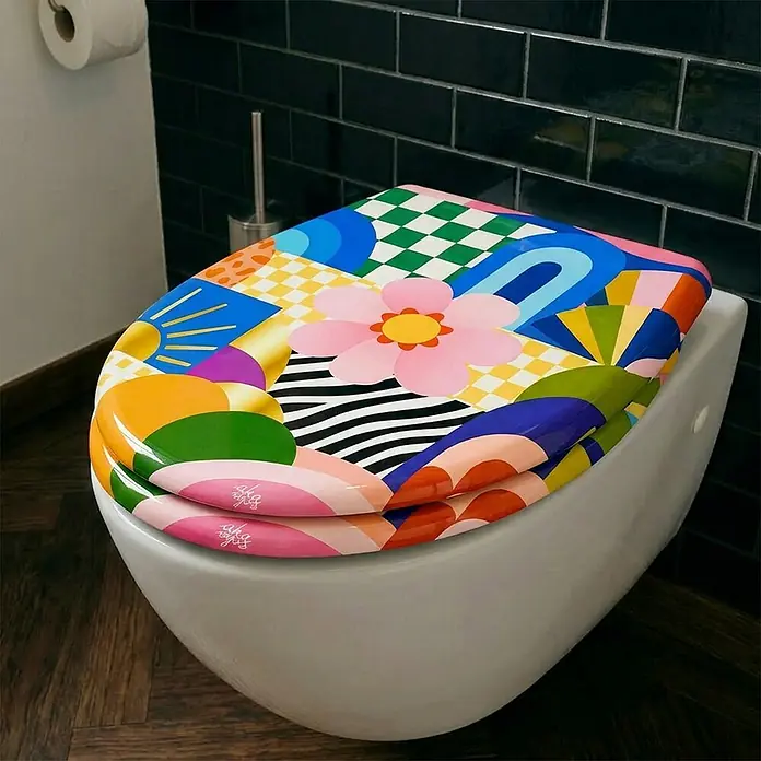 Wodea WC-Sitz   -  FlowerPower -  - Ein bunter, abstrakt gemusterter Toilettensitz mit geometrischen Formen, Sonne und rosa Blume auf einer weißen Toilette.