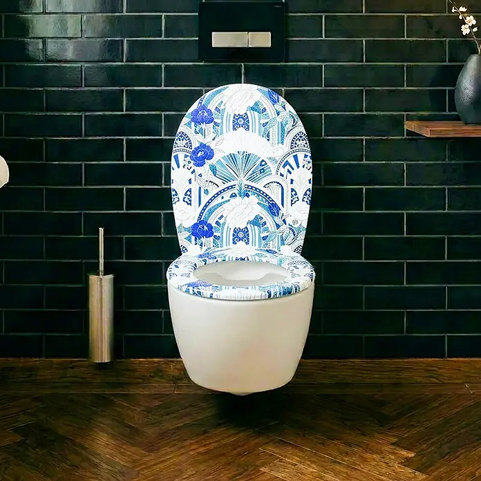 Wodea WC-Sitz   -  Wallpaper -  - Weiße Toilette mit blau-weiß gemustertem WC-Sitz, verziert mit einem aufwendigen Blumen- und Fächermuster.