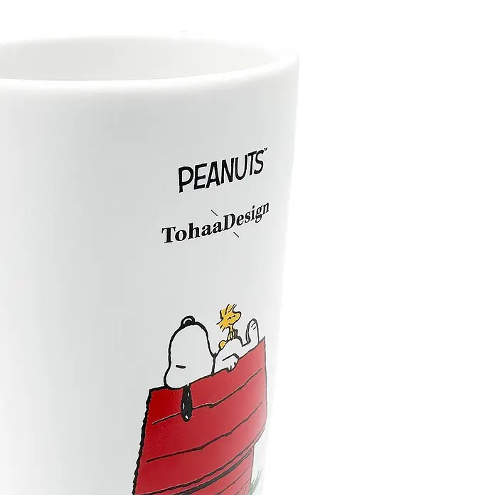 Tohaa Design Zahnputzbecher Peanuts Snoopy - Peanuts -  - Weiße Keramiktasse mit 'PEANUTS'- und 'TohaaDesign'-Aufschrift und einer Illustration von Snoopy und Woodstock in einer roten Hundehütte.