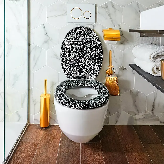 TohaaDesign WC-Sitz Cyborg - Skwak -  - Toilette mit schwarz-weißem Doodle-Sitz und goldenen Accessoires in einem modern gefliesten Bad.