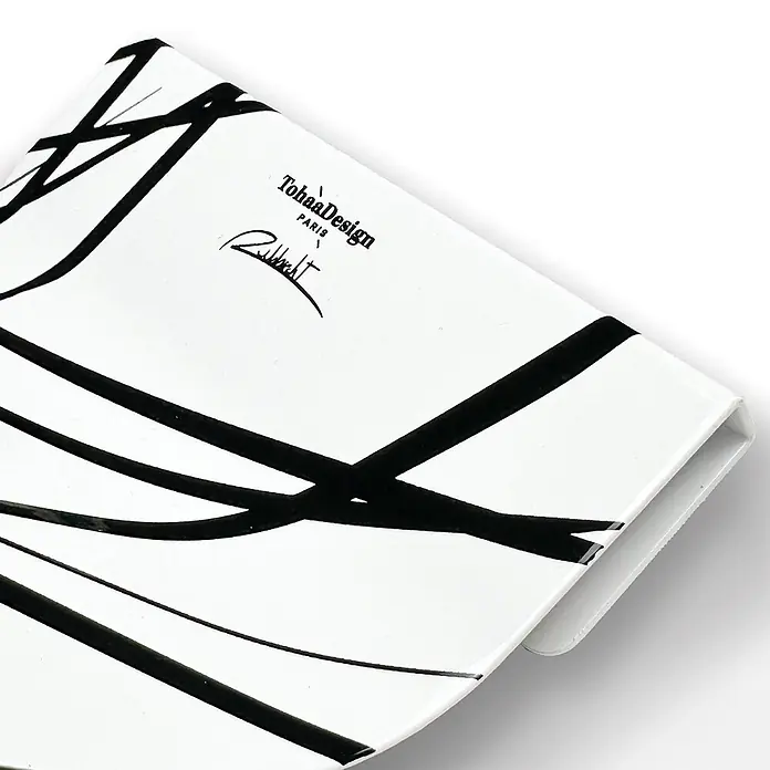Tohaa Design Toilettenpapierhalter Arrow - L. Rubbrecht -  - Weißes, rechteckiges Objekt mit abstrakten schwarzen Linien und "TohaaDesign PARIS" Branding.