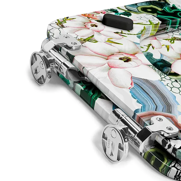 Tohaa Design WC-Sitz Algae Bloom Modern-D - Maison Christian Lacroix -  - Nahaufnahme eines Koffers mit Chromrädern und einem lebhaften Blumen- und Geologiemuster, mit Magnolien und Malachit.