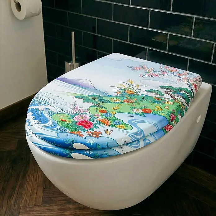 Wodea WC-Sitz   -  Kawai -  - Weiße Toilette mit einem verzierten Toilettensitz und -deckel mit detailliertem japanischen Landschafts- und Naturdesign in einem Badezimmer.