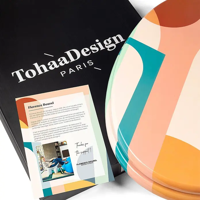 TohaaDesign WC-Sitz Roma - Florence Bourel -  - Gestapelte runde Tabletts mit lebhaften geometrischen Mustern in Pfirsich, Türkis und Orange, präsentiert mit Markenverpackung.