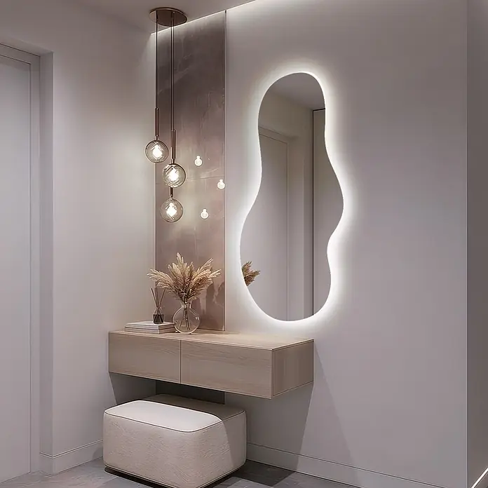 Unregelmäßiger LED-Spiegel -  - Moderne Diele mit unregelmäßig geformtem, hinterleuchtetem Spiegel, heller Holzkonsole, cremefarbenem Hocker und Messingpendelleuchten.