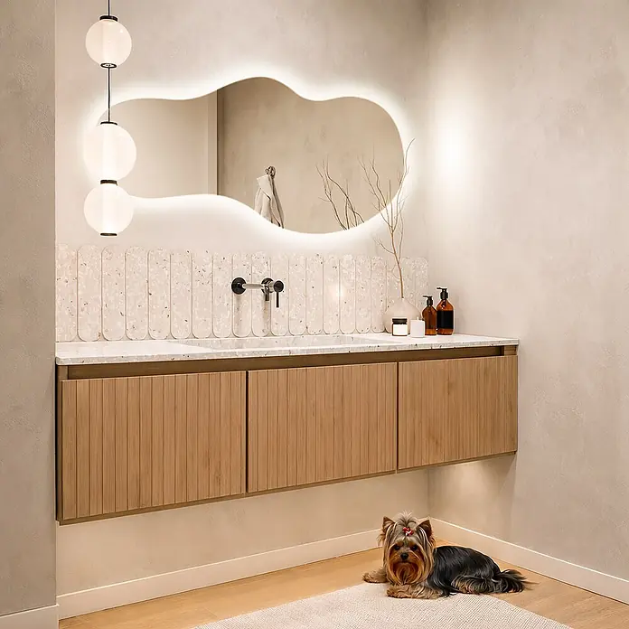Unregelmäßiger LED-Spiegel -  - Moderner Waschtisch mit hellem Holzschrank, Marmorplatte, beleuchtetem Spiegel und Pendelleuchten über Terrazzo-Fliesen.