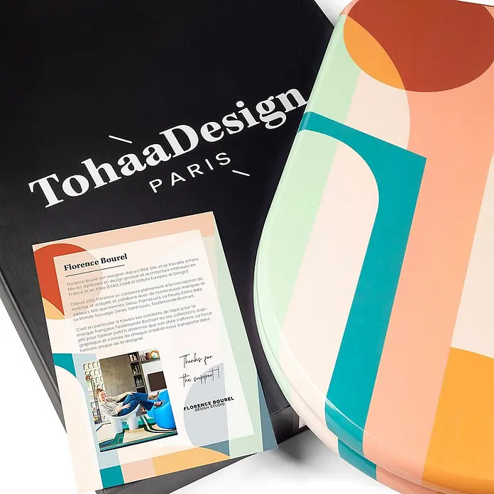 TohaaDesign WC-Sitz Roma Modern-D - Florence Bourel -  - Schwarze TohaaDesign Box mit weißem Logo und bunten, abstrakt gemusterten Artikeln, begleitet von einer Designer-Infokarte.