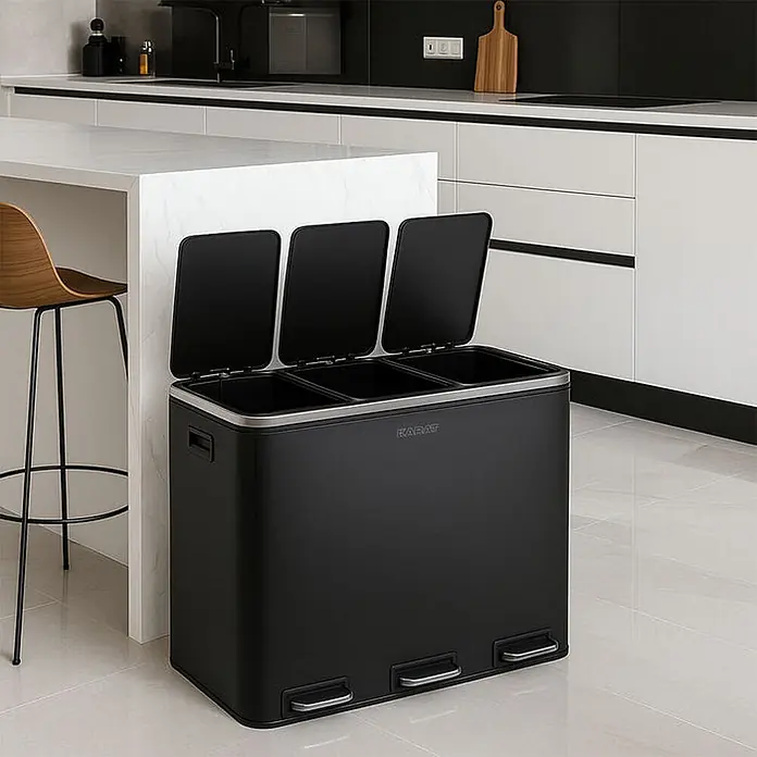 Floordirekt Mülleimer Felix 3 x 18 Liter Schwarz -  - Ein schwarzer Metall-Mülleimer mit drei offenen Fächern und Fußpedalen steht in einer modernen Küche zur Mülltrennung bereit.
