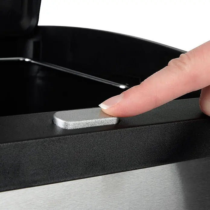 Floordirekt Mülleimer James mit Trennsystem und 3 Kammern 32 Liter -  - Ein Finger drückt einen silbernen Knopf an einem schwarzen Rand, um den Deckel eines Mülleimers aus gebürstetem Metall zu öffnen.
