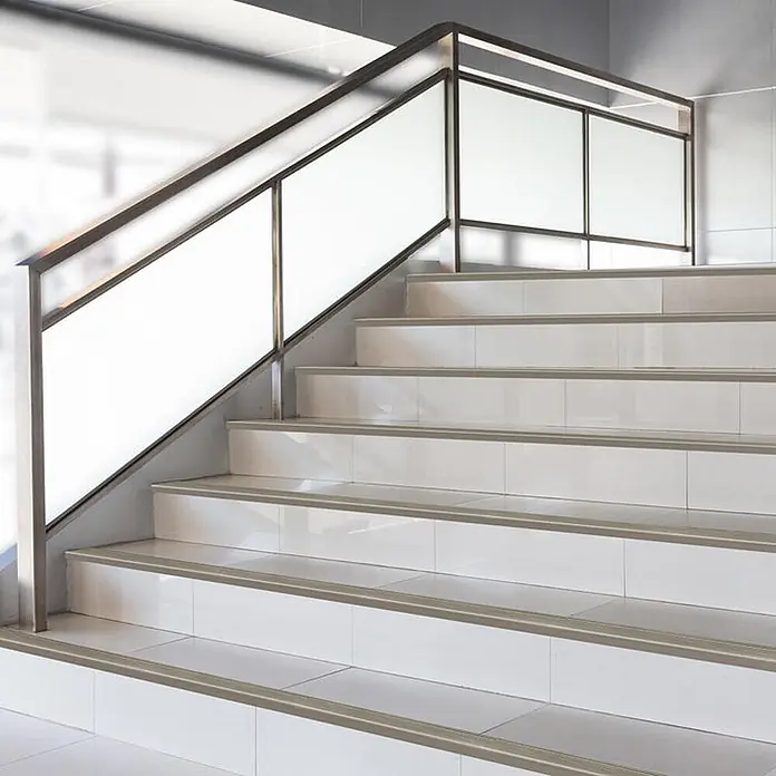 Floordirekt Treppenkantenprofil Safety 100 cm Bronze Hell - Aluminium, Bronze Dunkel, Eloxiert - Graue Antirutsch-Treppenprofile auf weißen gefliesten Stufen einer modernen Treppe.