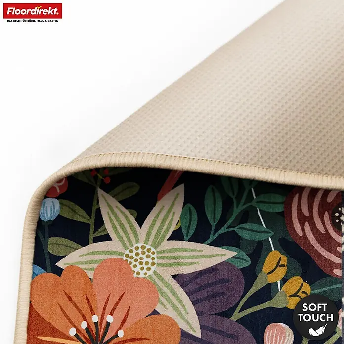 Floordirekt Kurzflorteppich Tropica 160 x 230 cm - Multicolor - Nahaufnahme eines bunten Blumenmuster-Teppichs, eingerollt, zeigt weiche Oberfläche und beige Anti-Rutsch-Waffelrückseite, betont Soft-Touch.