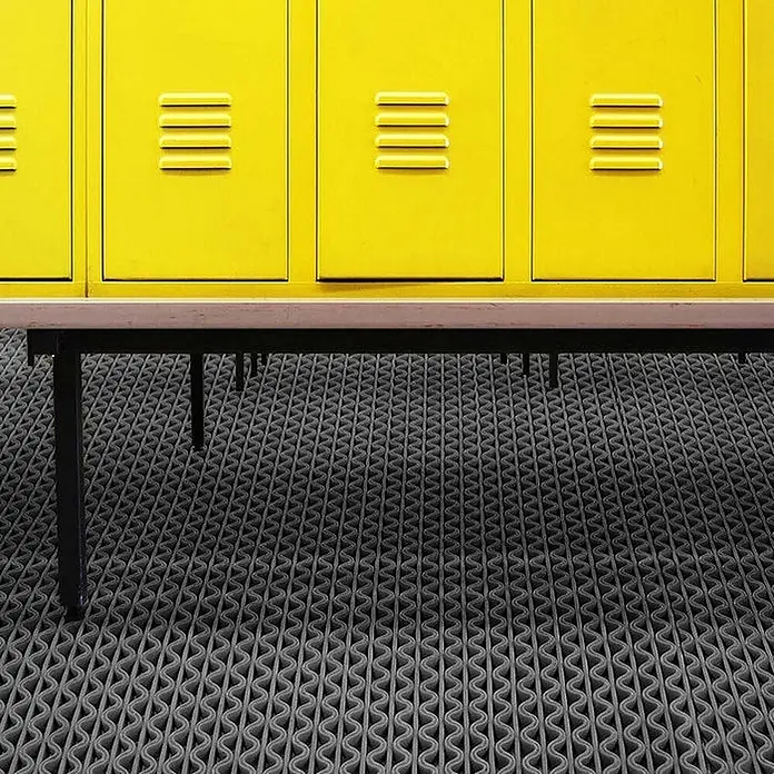 Floordirekt Antirutschmatte Anti-Slip für Barfußzonen - UV-beständig - Grau - 90 x 200 cm - Grau - Graue, wellenförmig gemusterte Bodenmatte in einem Umkleideraum mit gelben Spinden und einer Holzbank.