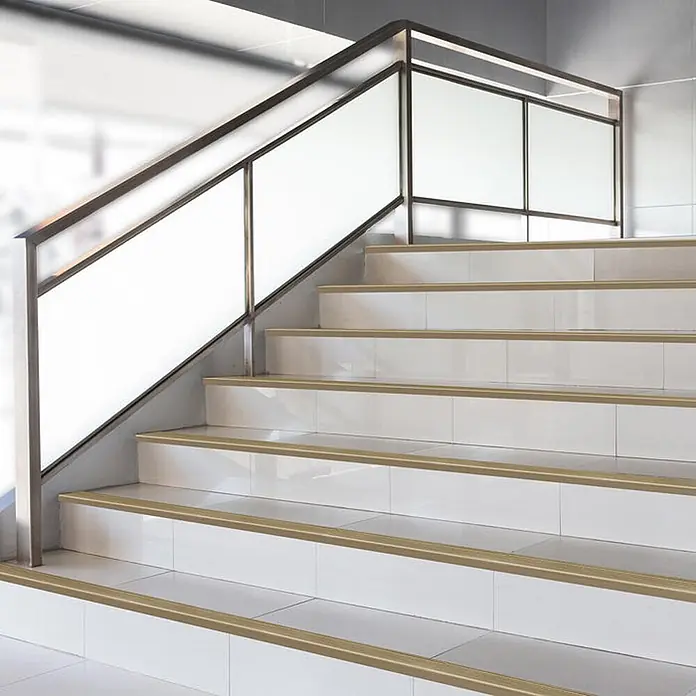 Floordirekt Stufenkantenprofil Safety Bronze Hell 100x5,3 cm Vorgebohrt -  - Goldbraune Treppenprofile auf weiß gefliesten Stufen, bieten Rutschschutz und verbessern die Optik.