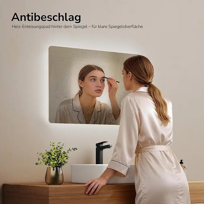 Emke Lichtspiegel Glowrim LM09 - 60 x 40 cm - Frau trägt Make-up vor einem beleuchteten Badspiegel mit klarer Antibeschlag-Oberfläche, während andere Bereiche beschlagen sind.