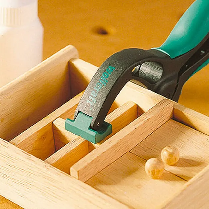 Wolfcraft Pinza con resorte FZ 60 - Anchura de sujeción: 60 mm, Apertura máxima: 60 mm - Primer plano de una abrazadera de una mano de Wolfcraft que asegura un proyecto de madera. Ideal para precisión.