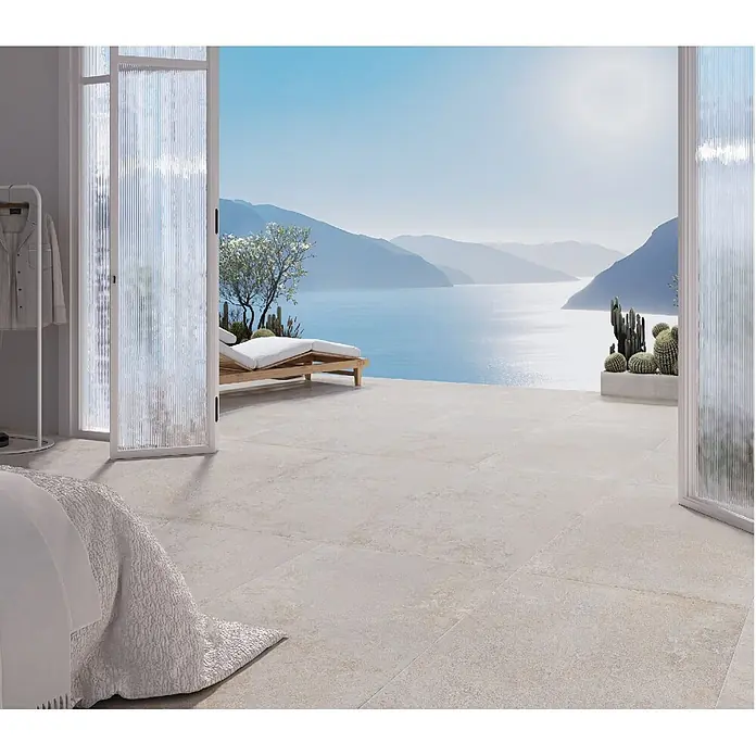 Feinsteinzeugfliese BARDENAS BONE – 60 x 120 cm, Betonoptik, Mat -  - Helle Bodenfliesen innen und außen, die einen nahtlosen Übergang von einem Raum zu einer Terrasse mit Meerblick schaffen.