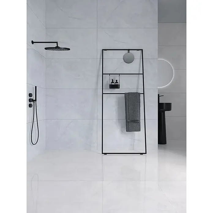 Feinsteinzeugfliese GINZA WHITE – 60 x 120 cm, Marmoroptik, Lappato -  - Moderne mattschwarze Duscharmaturen und ein schwarzer Leiter-Handtuchhalter mit Spiegel und Flaschen in einem minimalistischen Bad.