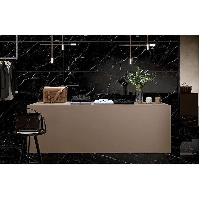 Feinsteinzeugfliese SAINT LAURENT – 60 x 120 cm, Marmoroptik, Brillant -  - Elegante schwarze Fliesen in Marmoroptik mit weißer Maserung bedecken Wände und Boden eines modernen Ausstellungsraums.