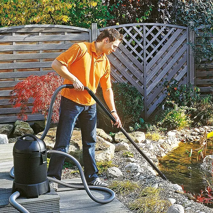Neptun Classic Teichschlammsauger NCTS-O 1400 - 1.400 W, Tankvolumen: 30 l - Ein Mann reinigt einen Gartenteich mit einem Teichsauger, der neben ihm auf einer Holzterrasse steht.
