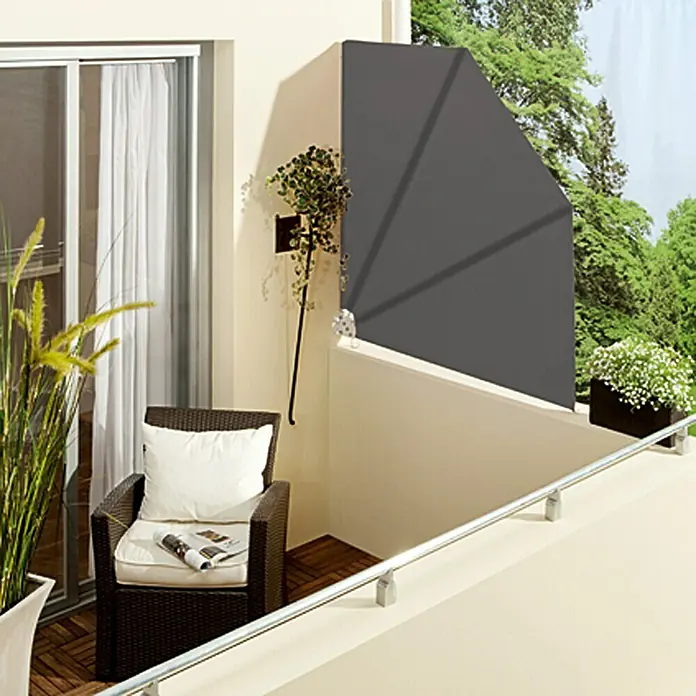 Sunfun Abanico para balcón - Antracita, 1,4 x 1,4 m - Escena de balcón con un elegante toldo lateral gris que ofrece privacidad y sombra. Acogedora zona de estar con sillón y plantas.