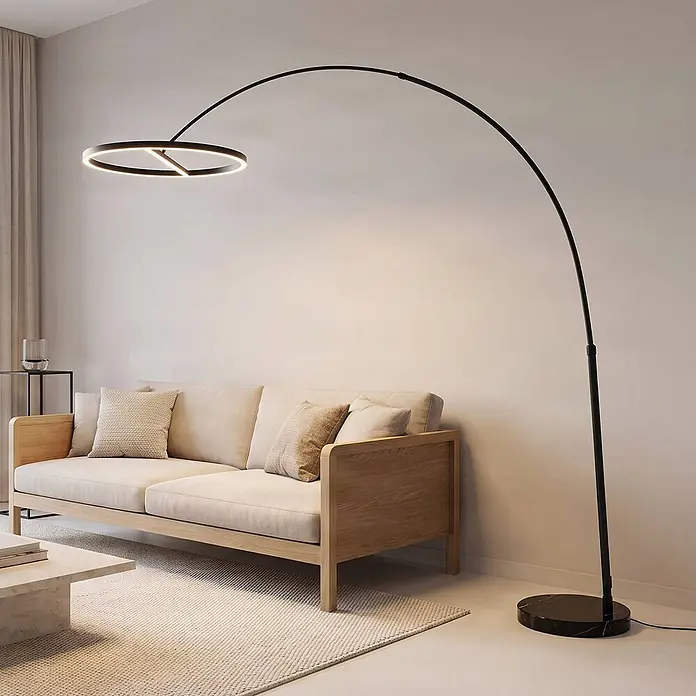 Lucande LED Stehlampe in schwarz, Bogenlampe Wohnzimmer -  - Schwarze Bogen-Stehlampe mit rundem LED-Kopf und schwarzem Marmorfuß, beleuchtet ein helles Sofa.