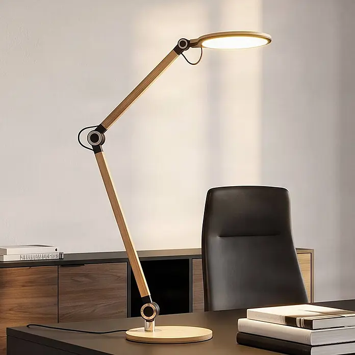 Lindby LED Schreibtischlampe in gold, dimmbar Tischlampe -  - Verstellbare Schreibtischlampe aus Holz mit runder LED-Leuchte, die einen dunklen Schreibtisch in einem Büro beleuchtet.