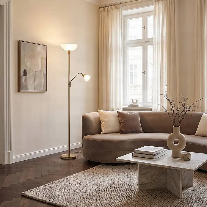 Lindby Stehlampe, Deckenfluter verstellbarer Lesearm, Standleuchte -  - Messingfarbene Stehleuchte mit Deckenfluter und verstellbarer Leselampe, neben einem geschwungenen Sofa im warmen Wohnzimmer.