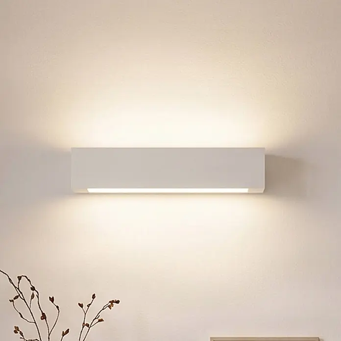 Lindby Wandleuchte innen in weiß, up down Wandlampe -  - Weiße rechteckige LED-Wandleuchte wirft warmes Auf- und Ablicht an eine strukturierte Wand.