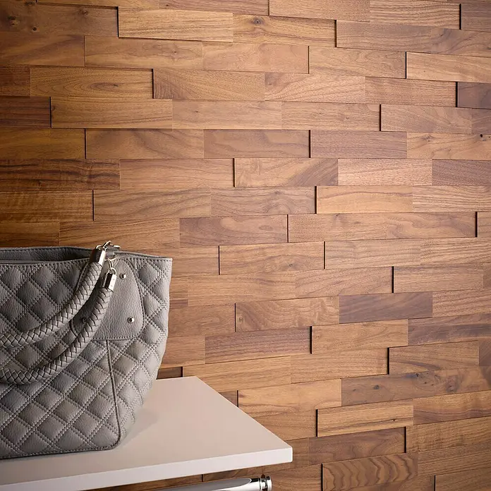 Wodewa Holzriemchen 200 Nussbaum - L x B: 200 x 50 mm, 2 mm - 6 mm, Max. Anwendungsfläche: 1 m², UV-geölt - Naheaufnahme einer eleganten grauen Handtasche auf einem Regal, vor einer Wand mit Holzpaneelen. Das Produkt wird optimal präsentiert.