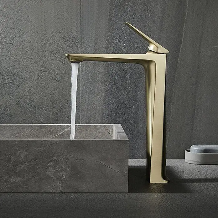 Waschtischarmatur 7857 Gold -  - Goldfarbene moderne Armatur mit fließendem Wasser in ein rechteckiges Steinwaschbecken.