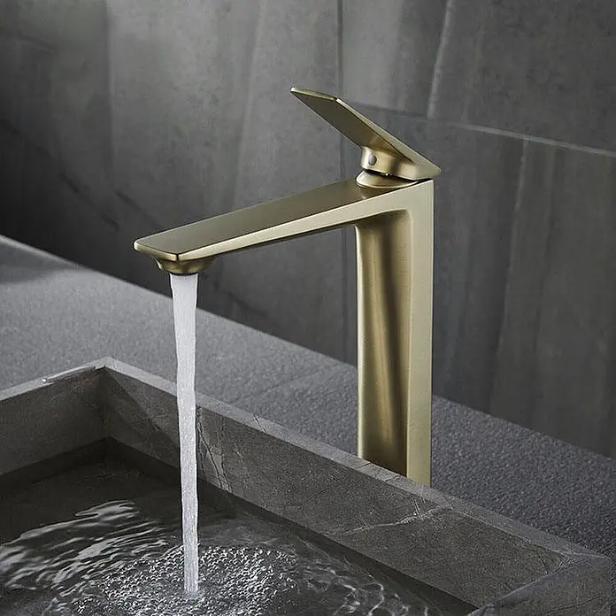 Waschtischarmatur 7857 Gold -  - Ein moderner matter Goldwasserhahn mit fließendem Wasser in ein dunkles Steinwaschbecken.