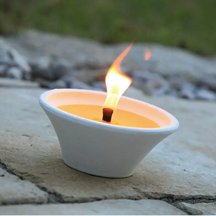 Duftkerze Terracotta Schale - Citronella, Ø x H: 17 x 7,5 cm - Nahaufnahme einer Gartenfackel in einer weißen Schale auf Steinboden mit lebendiger Flamme, ideal für stimmungsvolle Außenbeleuchtung.