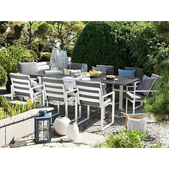 17-tlg Gartentisch Set PANCOLE in Grau/Weiß -  - Große Outdoor-Essgruppe mit dunkelgrauem Tisch und weißen Stühlen mit grauen Kissen, in einem üppigen Garten.