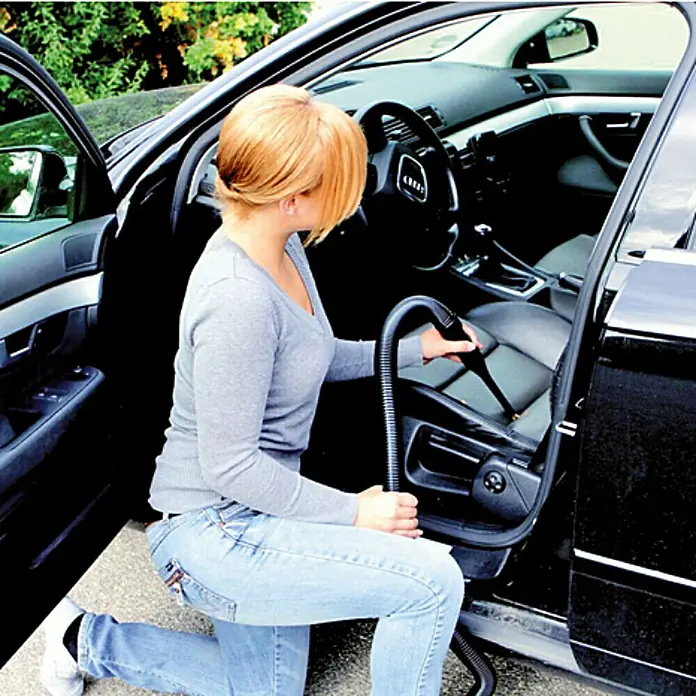 Scheppach Equipo de aspiración HD2P - Potencia de aire máx.: 120 m³/h, Capacidad del depósito: 5 l, 1.250 W - Mujer aspirando el interior de su coche para mantenerlo limpio y ordenado con una aspiradora de coche.