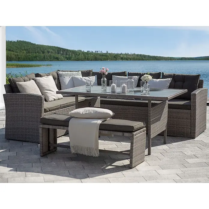 13-tlg Lounge Set VITERBO in Grau -  - Graue Rattan-Gartenmöbel mit Ecksofa, Tisch und Bank auf einer Terrasse am See.