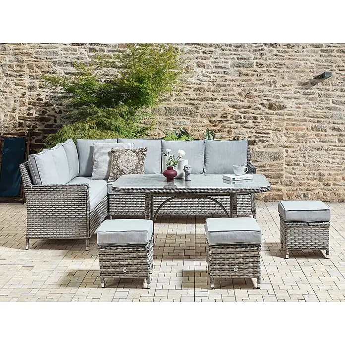 5-tlg Lounge Set LACONA in Grau rechtsseitig -  - Graues Rattan-Ecksofa-Set für den Außenbereich mit Glastisch und drei Hockern, hellgrauen Kissen, auf einer gepflasterten Terrasse.