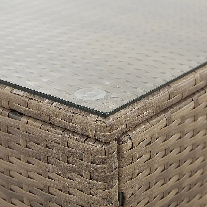 21-tlg Lounge Set BELVEDERE in Braun/Weiß -  - Nahaufnahme eines braunen Rattan-Tisches für den Außenbereich mit klarer Glasplatte, gehalten von einem Saugnapf.