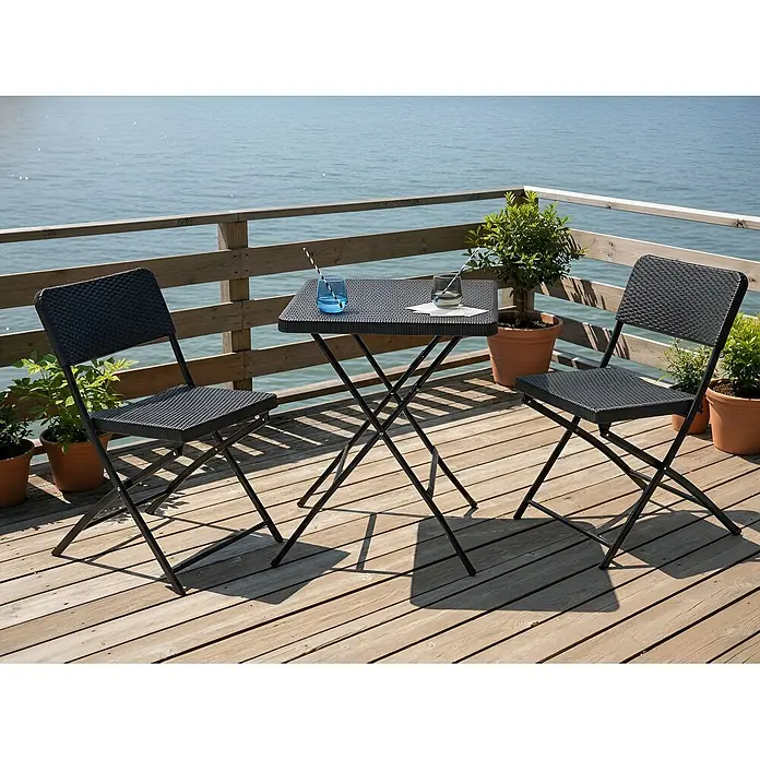 3-tlg Bistro Set TRAPPETO in Schwarz -  - Schwarzes klappbares Terrassenset mit Tisch und zwei Stühlen in Flechtoptik auf Holzdeck am Meer, mit Getränken und Topfpflanzen.