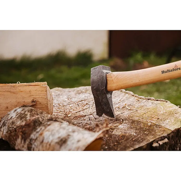 Hultafors KVILLINGE Spaltaxt -  - Hultafors Axt mit Metallkopf und Holzgriff steckt in einem Hackklotz, mit Holzscheiten daneben.