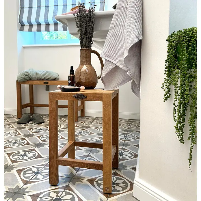 Bad Beistelltisch Holz Viola Teak massiv mit Gummifüßen -  - Kleiner Holzschemel im Badezimmer, der Lavendel und Pflegeprodukte neben einem Waschbecken hält.
