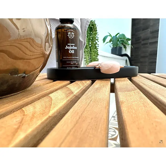 Bad Beistelltisch Holz Viola Teak massiv mit Gummifüßen -  - Flasche Bio-Jojobaöl und Rosenquarz-Roller auf schwarzem Tablett auf Holztisch.