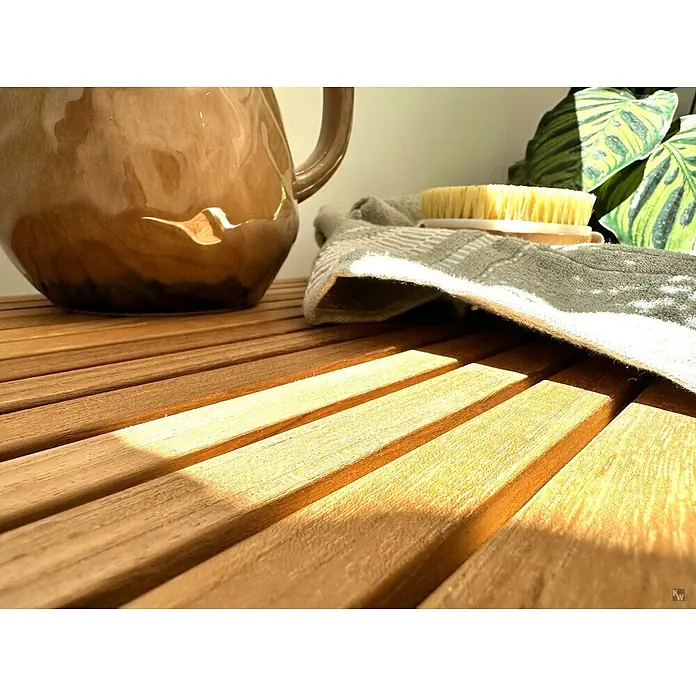 Badregal Holz Bella Teak massiv mit Gummifüßen montiert geliefert -  - Braune Keramikkaraffe auf einer Holzlattenfläche mit Körperbürste und Handtuch, in natürlichem Licht.