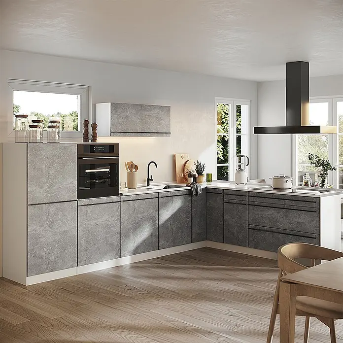 Eckküche R-Line 327 cm Beton Art.-Nr. 67577 -  - Eine moderne L-förmige Küche mit grauen Beton-Optik-Schränken, integriertem schwarzem Backofen und schwarzer Inselhaube in einem hellen Raum.