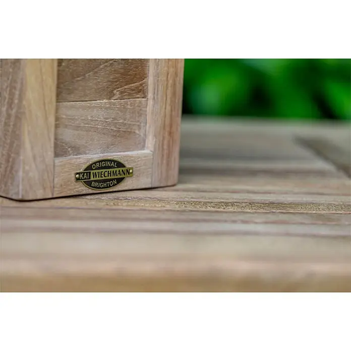 Teak Nistkasten für Gartenvögel als wetterfestes Vogelhaus Massivholz -  - Hölzernes Objekt mit ovalem, messingfarbenem Etikett „ORIGINAL KAI WIECHMANN BRIGHTON“ auf einem Holztisch.