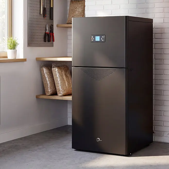 Sannover Pelletkessel kompakt Alva 30,7 kW -  - Dunkelgrauer Pelletkessel mit Digitalanzeige, in einem Hauswirtschaftsraum mit Holzpellets in Regalen.